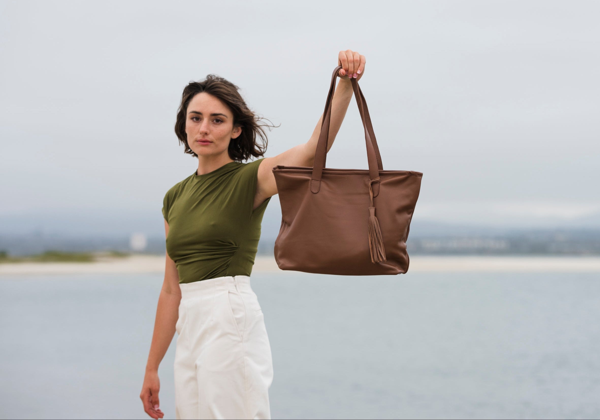 Woman holding a brown tote bag against a plain background