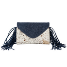 A fringe clutch bag featuring a dark navy blue suede envelope-style flap with floral embossing, a cowhide-patterned body, and long matching navy blue fringe tassels on both sides, shown against a plain white background.