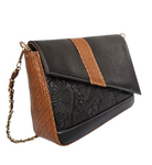 Black and brown handbag with embossed design on a white background